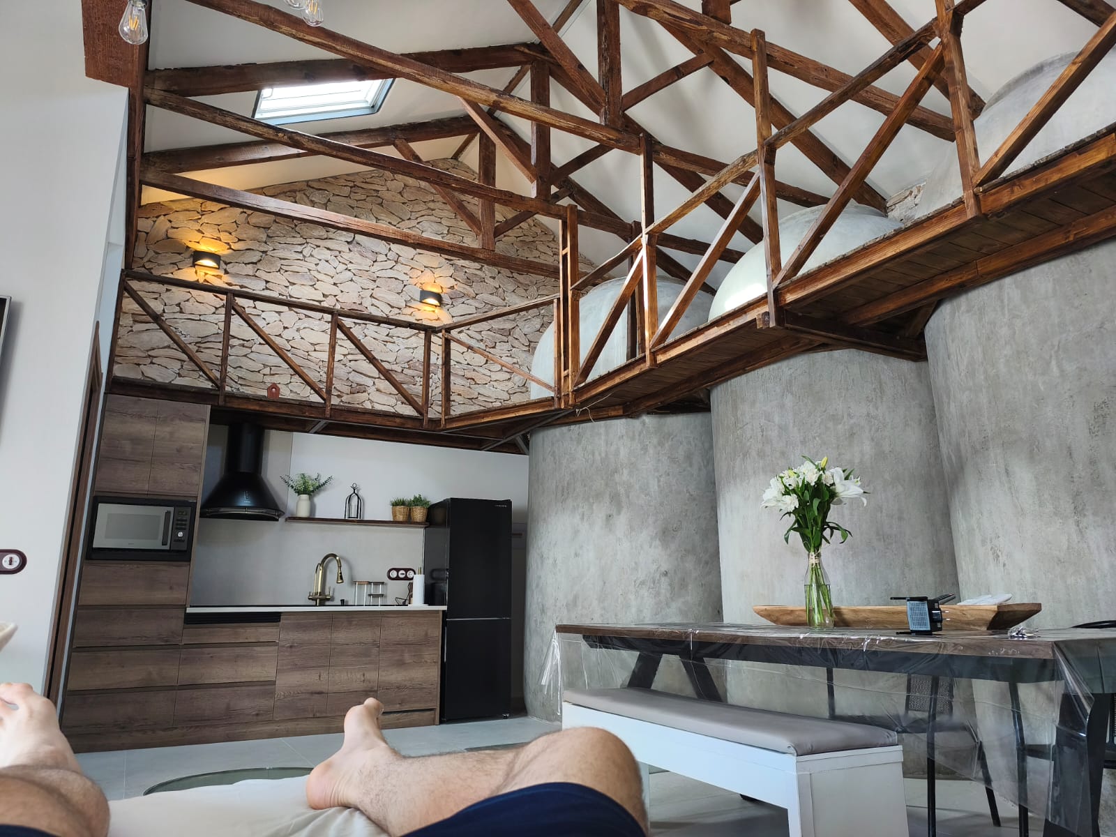 Salón abierto con cocina, piedra y vigas de madera